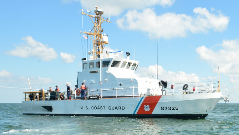 A white Coast Guard vessel with a red strip on its hull on the sea during a bright sunny day