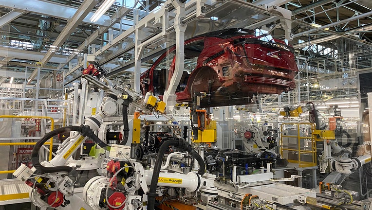 Robotic arms integrated into the powertrain of the Ariya model electric vehicle on the assembly line at Nissan's Tochigi plant in Kaminokawa city, Tochigi prefecture, Japan on Friday, October 8, 2021 (AP Photo / Yuri Kageyama)