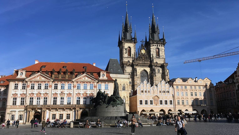 A church and other buildings in Old Town Square in Prague under a deep blue sky