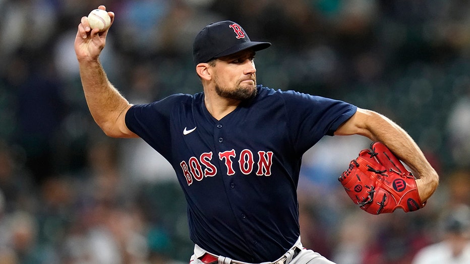 Red Sox pitcher Nathan Eovaldi, wearing dark blue uniform jersey and cap, prepares to throw a baseball