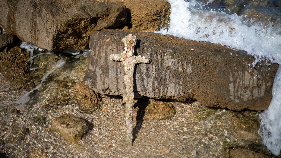 An ancient sword propped up against a rock on the Mediterranean coast