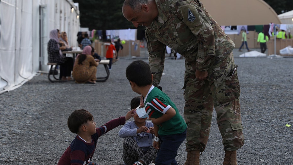 Man in uniform hands candy to some children