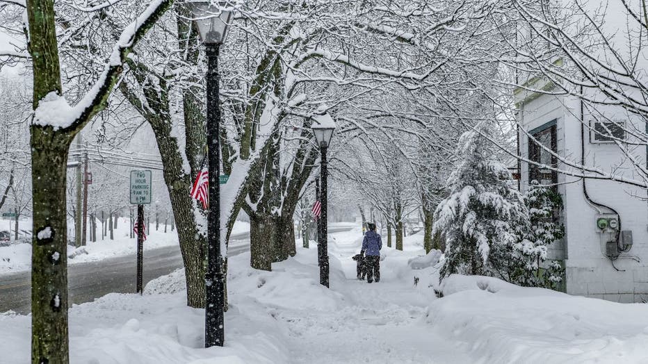 A woman walks her dog on a snow-covered sidewalk in Milford, Pennsylvania.