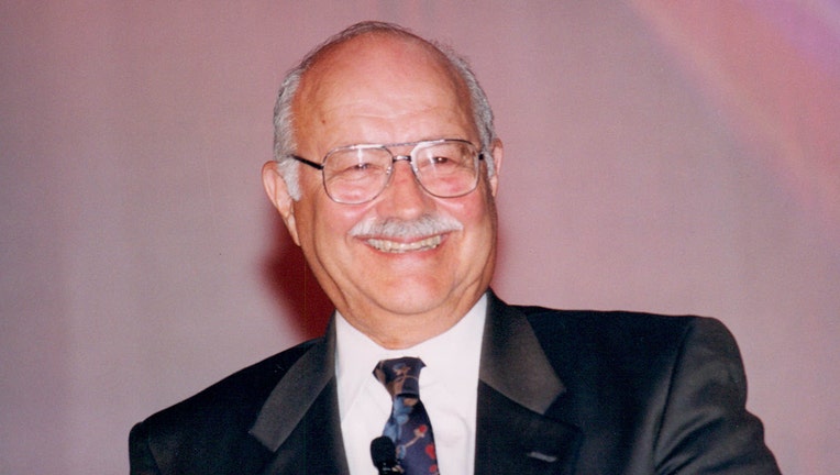 A man wearing glasses and a suit smiles