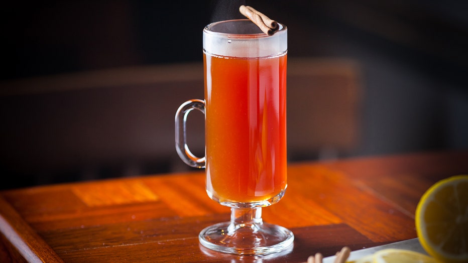 A toddy glass with a hot beverage topped with a cinnamon stick