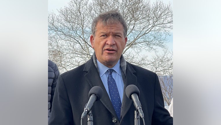 Man with gray hair speaks into two microphones