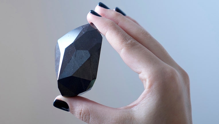 Closeup of a large black diamond held in a person's hand