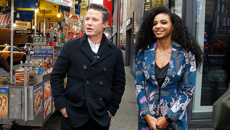 Billy Bush and Miss USA 2019 Cheslie Kryst enjoy a hot dog in times square during "Extra" at The Levi's Store Times Square on November 18, 2019 in New York City. (Photo by John Lamparski/Getty Images)