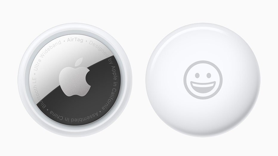 Front and back of an Apple AirTag device; device is white and silver, one side had the Apple logo, the other has a smiley face emoji