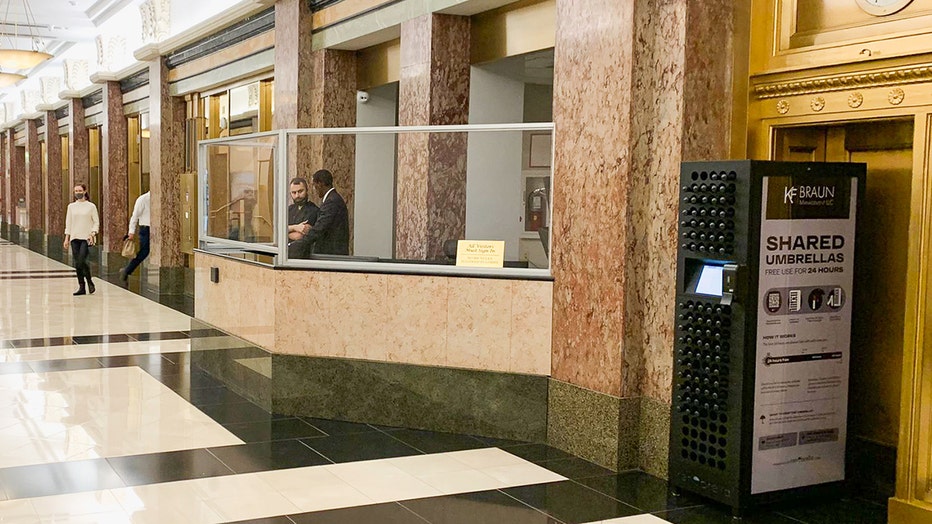 A lobby with a reception desk with plexiglass and a kiosk