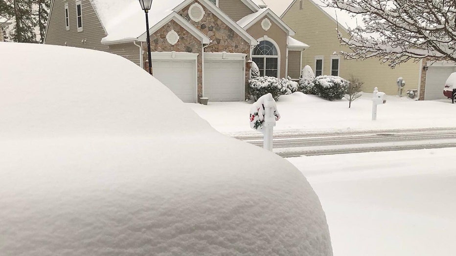 Freshly fallen snow on cars, sidewalks, streets, homes