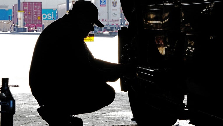 FILE - A mechanic checks out a semi-truck. 