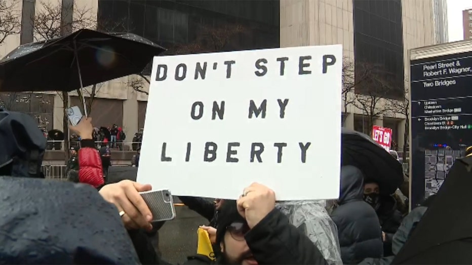 A man holds a sign that reads 'Don't step on my liberty'