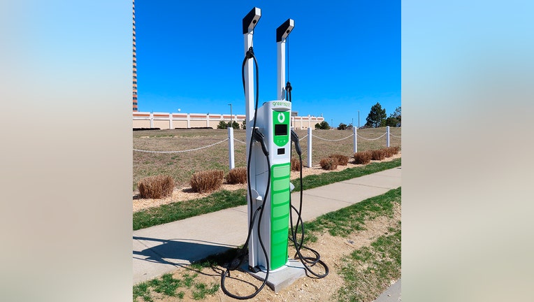 A green and white charging station for electric cars on the side of a street