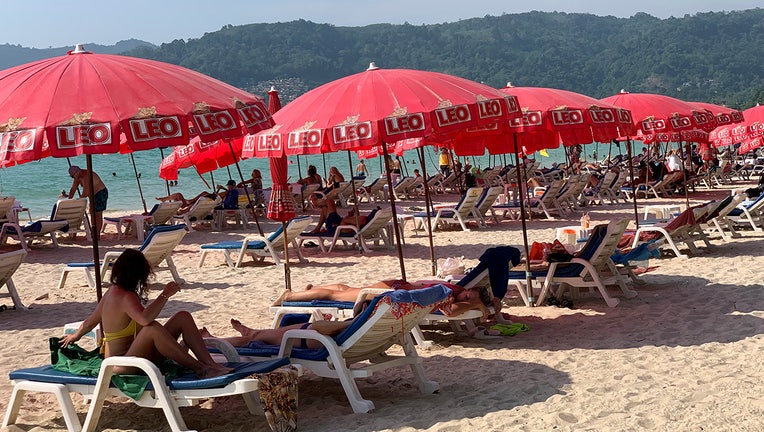 Tourists lounge under umbrellas along Patong Beach in Phuket, Thailand, Friday, March 11, 2022. (AP Photo/Salinee Prab)