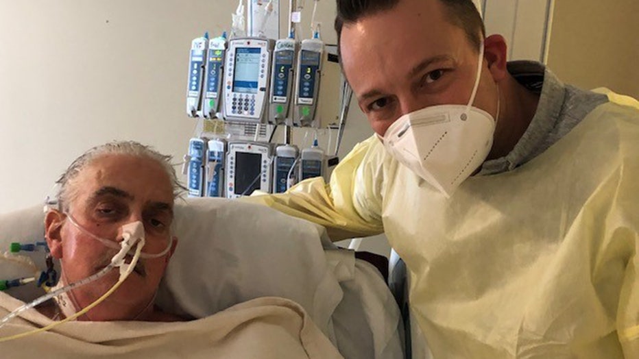 In this photo provided by the University of Maryland School of Medicine, David Bennett Jr., right, stands next to his father's hospital bed in Baltimore, Md., on Jan. 12, 2022, five days after doctors transplanted a pig heart into Bennett Sr. (University of Maryland School of Medicine)
