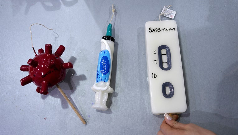 Candles that resemble a COVID-19 test kit, a vaccination syringe and a virus cell