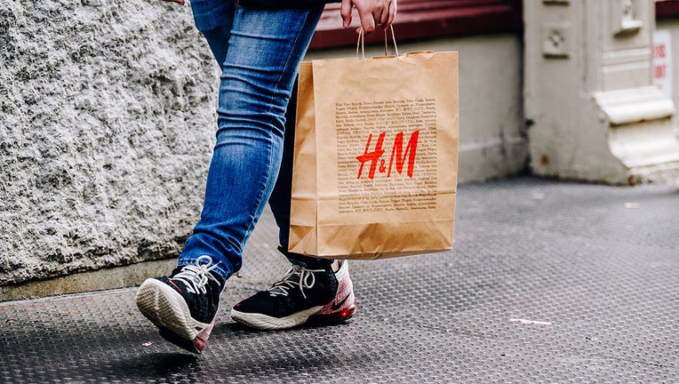 A pedestrian carries a Hennes & Mauritz (H&M) shopping bag in the SoHo neighborhood of New York, U.S., on Sunday, Oct. 24, 2021. (Nina Westervelt/Bloomberg via Getty Images)
