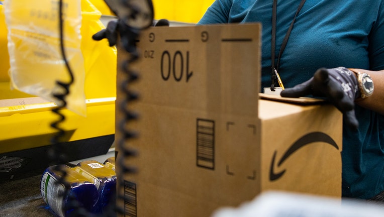 Closeup of a worker's gloved hands handling an Amazon package inside a warehouse