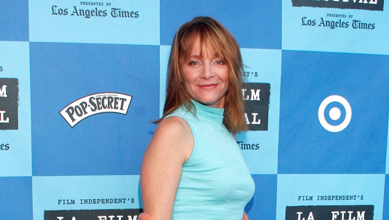 Actress Mara Mara seen in a head-and-shoulders photo; she looks at the camera and smiles; she wears a light blue sleeveless turtleneck; her hair is reddish blond