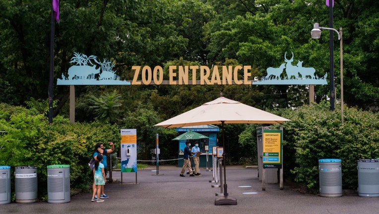 Visitors stand at an entrance to the Bronx Zoo in the Bronx borough of New York, U.S., on Friday, July 24, 2020.