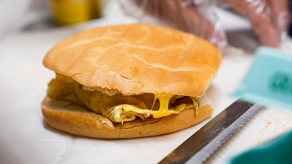 Hector Perez prepares to wrap a bacon, egg and cheese sandwich at a bodega in the Bronx section of New York, Friday, July 22, 2022. (AP Photo/Seth Wenig)