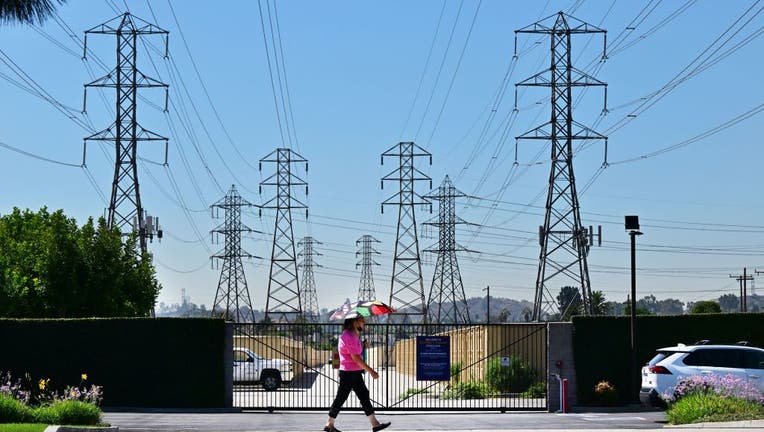 A pedestrian uses an umbrella to shield themself from the hot sun while walking past power lines in Rosemead, California, on August 31, 2022. (Photo by FREDERIC J. BROWN/AFP via Getty Images)