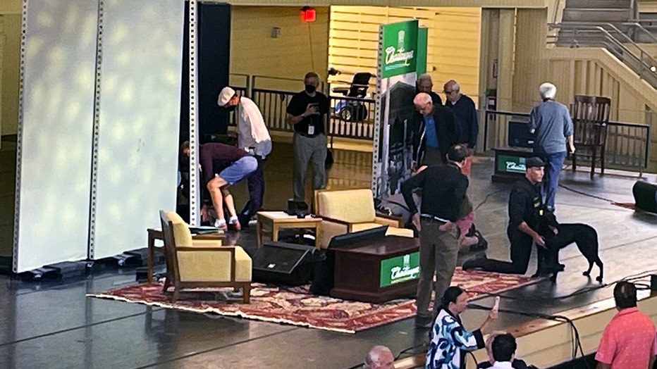 Author Salman Rushdie, behind screen left, is tended to after he was attacked during a lecture, Friday, Aug. 12, 2022, at the Chautauqua Institution in Chautauqua, N.Y. (AP Photo/Joshua Goodman)