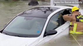 Watch: Firefighters smash car window to rescue woman from Ian floodwaters