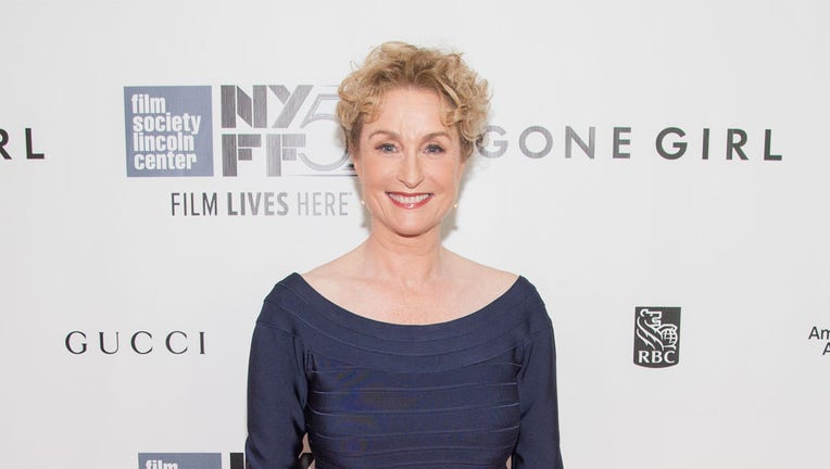 Head and shoulders image of actress Lisa Banes; she wears a blue scooped-neck dress; she smiles