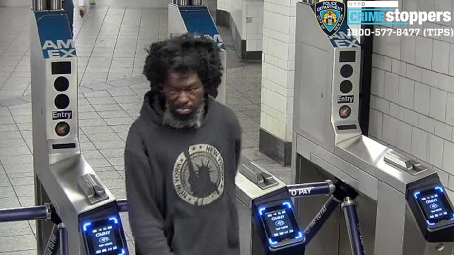 A man in a sweatshirt walks through a subway turnstile
