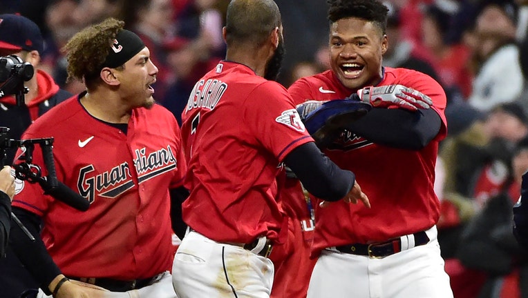Cleveland Guardians' Oscar Gonzalez, right, and Josh Naylor, left, celebrate with Amed Rosario, center, after the Guardians defeated the New York Yankees 6-5 in Game 3 of a baseball AL Division Series, Saturday, Oct. 15, 2022, in Cleveland. (AP Photo/Phil Long)
