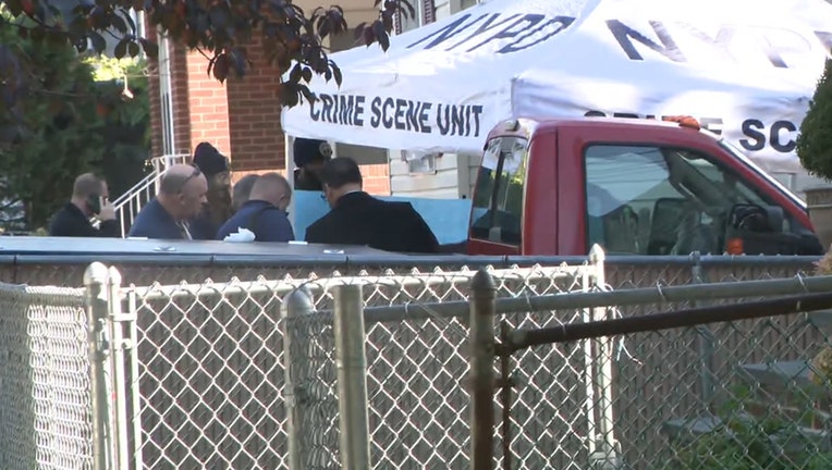 Cops stand near a white crime scene tent outside a house