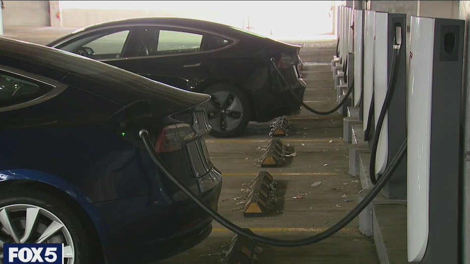 Two electric vehicles plugged into charging stations at a parking garage