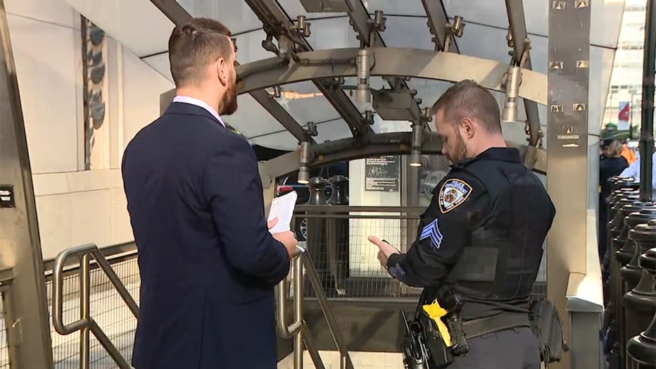 A police sergeant and a detective stand outside a subway station entrance