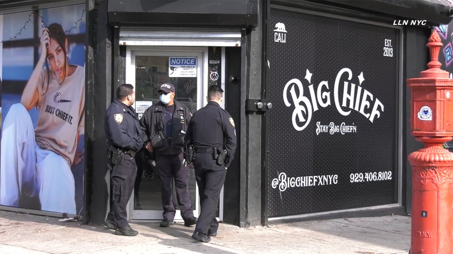 3 uniformed officers stand in front of a glass door of a smoke shop