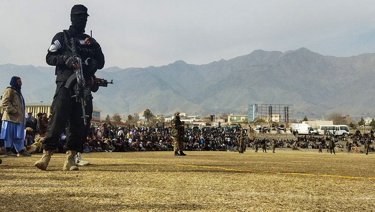 A Taliban security personnel stands guard as people attend to watch publicly flogging of women and men at a football stadium in Charikar city of Parwan province on December 8, 2022. (Photo by -/AFP via Getty Images)