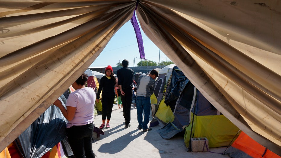 Migrants walk by their tents in the Senda de Vida 2 shelter in Reynosa, Mexico, Thursday, Dec. 15, 2022. Nearly three thousand people cram inside the vast compound of tents over cement or gravel by the Rio Grande, steps from the border with the United States, and many more line up outside hoping to come in to relatively safety from the cartels that prey on migrants. (AP Photo/Giovanna Dell'Orto)