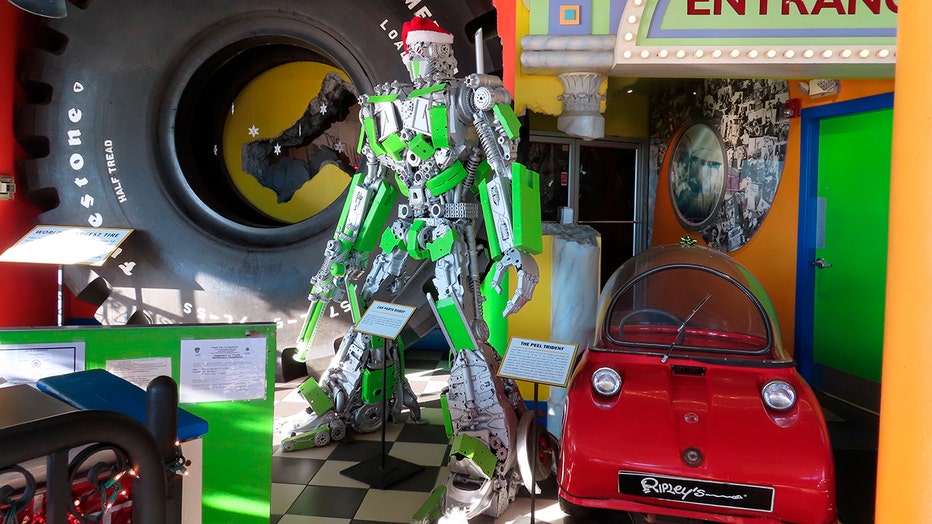 A small red car, a green robot, a tire for a monster truck and other items