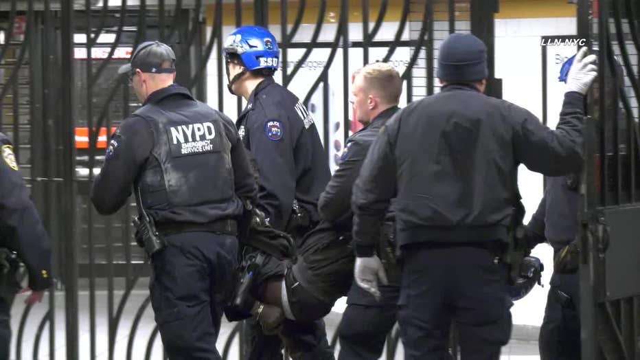 The suspect in a hammer attack is carried by NYPD officers in a Manhattan subway station.