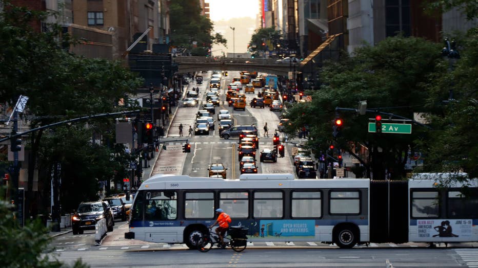 An MTA bus and cyclist cross 42nd Street as the sun sets on July 10, 2022, in New York City.(Photo by Gary Hershorn/Getty Images)