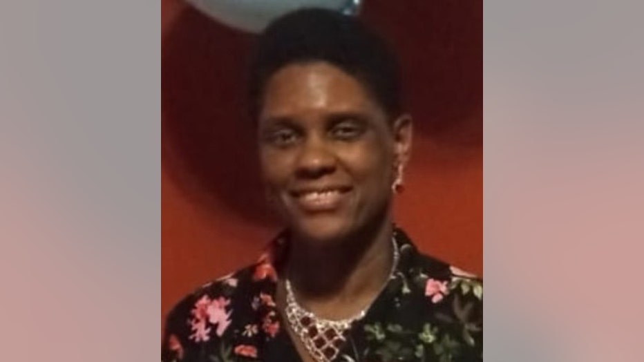 Smiling woman; she has short hair; she wears a floral outfit