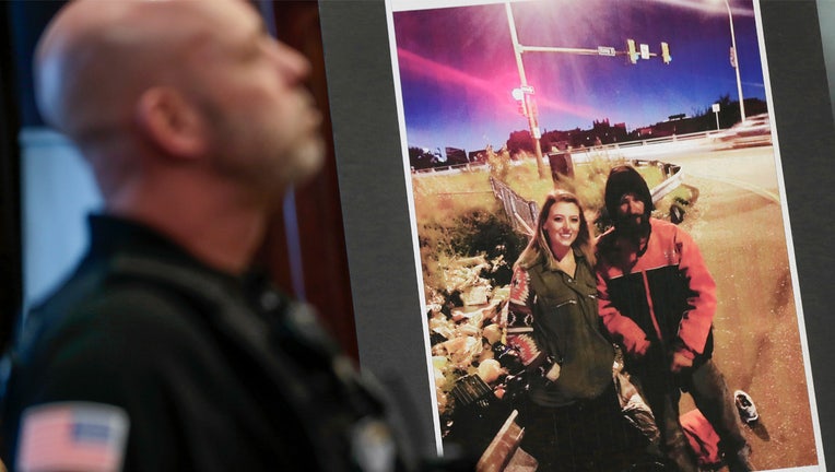 FILE - A law enforcement official stands next to a picture of Katelyn McClure and Johnny Bobbitt Jr., on display during a news conference in Mt. Holly, N.J., Thursday, Nov. 15, 2018. A New Jersey judge sentenced McClure to a term of one year and one day in prison, for her role in a scam that raised $400,000 using a fake story about Bobbitt who was a homeless veteran. (AP Photo/Seth Wenig, File)