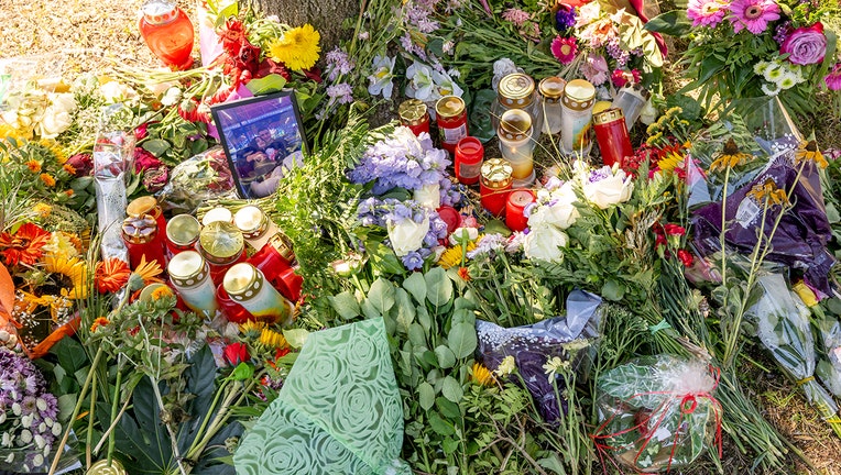Flowers, candles and pictures lie by a tree near which a female body was discovered in a passenger car on Aug. 17, 2022.