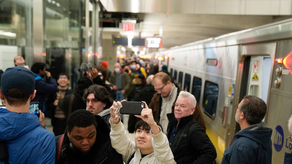 Riders take photos and videos as they exit the first Long Island Railroad train to arrive in Grand Central Station in New York, Wednesday, Jan. 25, 2023. After years of delays and massive cost overruns, one of the world's most expensive railway projects on Wednesday began shuttling its first passengers between Long Island to a new annex to New York City's iconic Grand Central Terminal. (AP Photo/Seth Wenig)