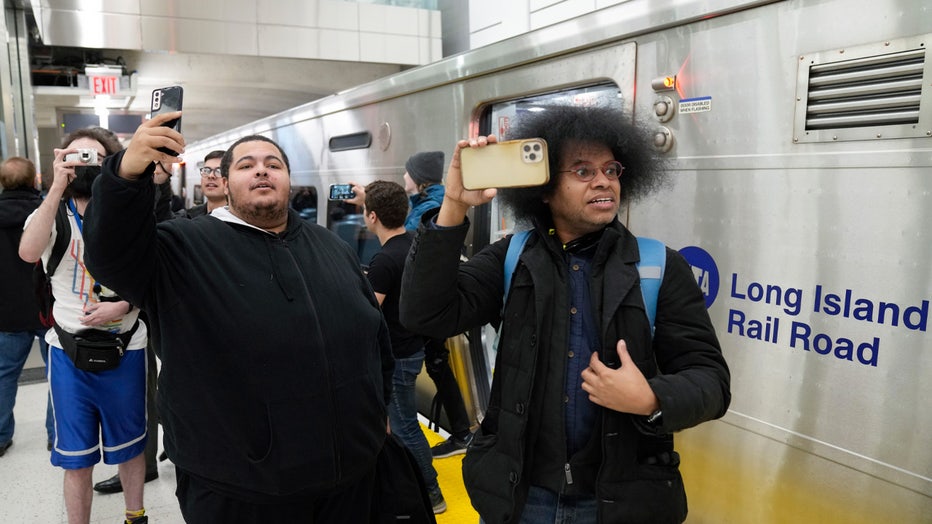 Riders take photos and videos as they exit the first Long Island Railroad train to arrive in Grand Central Station in New York, Wednesday, Jan. 25, 2023. After years of delays and massive cost overruns, one of the world's most expensive railway projects on Wednesday began shuttling its first passengers between Long Island to a new annex to New York City's iconic Grand Central Terminal. (AP Photo/Seth Wenig)