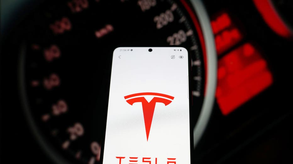 In this photo illustration a car brand logo "Tesla" seen