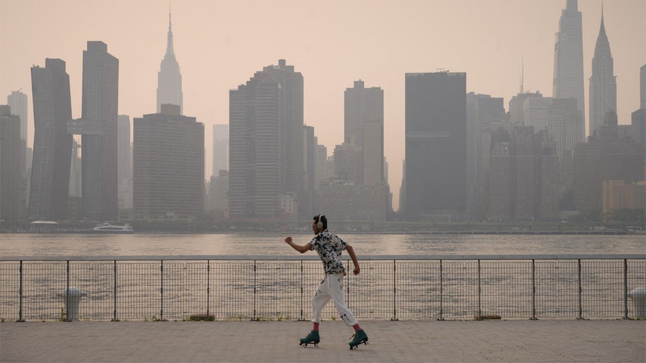 TOPSHOT - A man skates before the Manhattan city skyline at a park in the Brooklyn borough of New York on July 20, 2021. - Domestic media reported that smoke from wilfires buring on the west coast had made its way across the country as World Air Quality project published an air quality index reading of 172, or 'unhealthy' for New York city. (Photo by Ed JONES / AFP) (Photo by ED JONES/AFP via Getty Images)