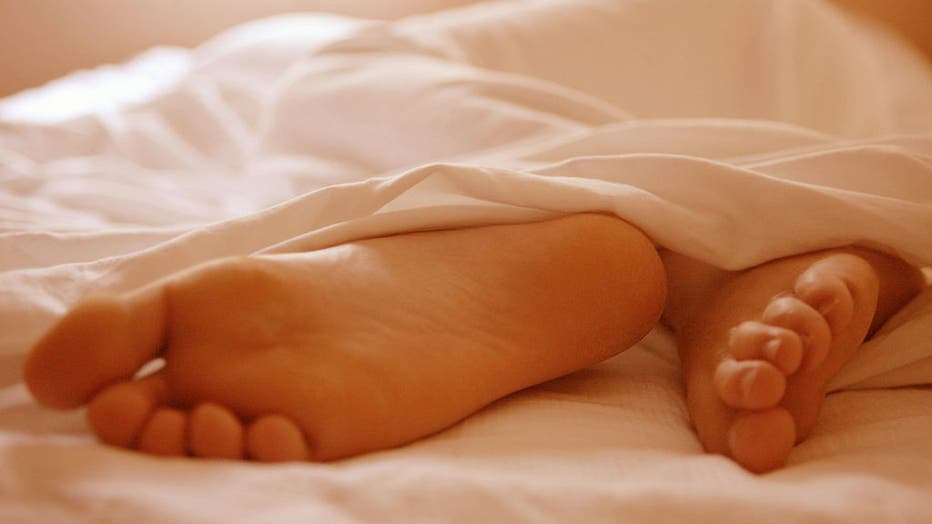 Man Sleeping,his feet sticking out from under the bed sheets