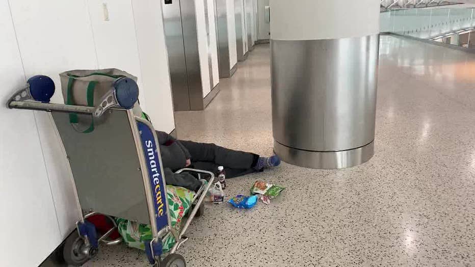 A person sleeps on the floor at JFK Airport.